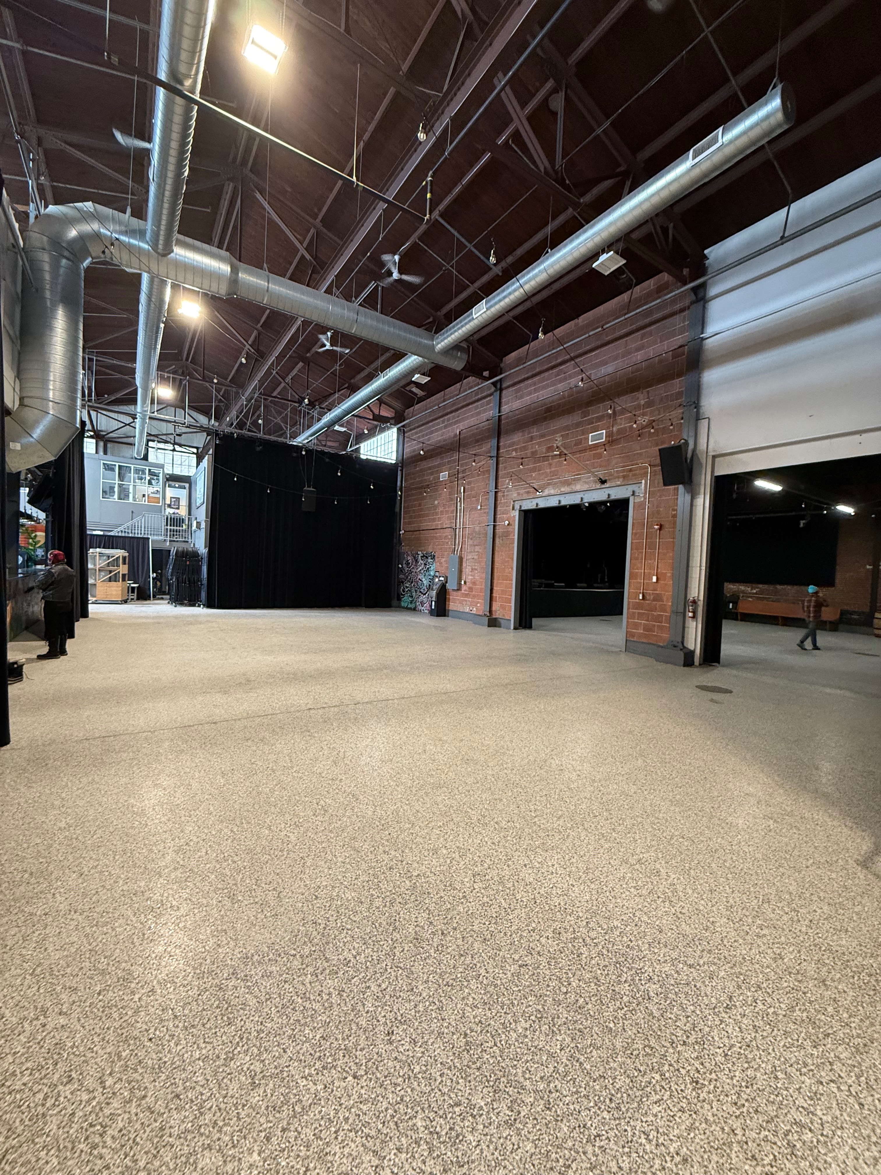 Interior view of Bridgeworks venue showing industrial space with exposed brick walls, high ceilings, and polished concrete floors